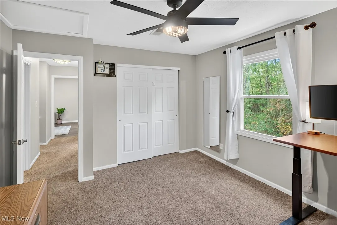 Bedroom featuring light colored carpet, attic access, and a ceiling fan