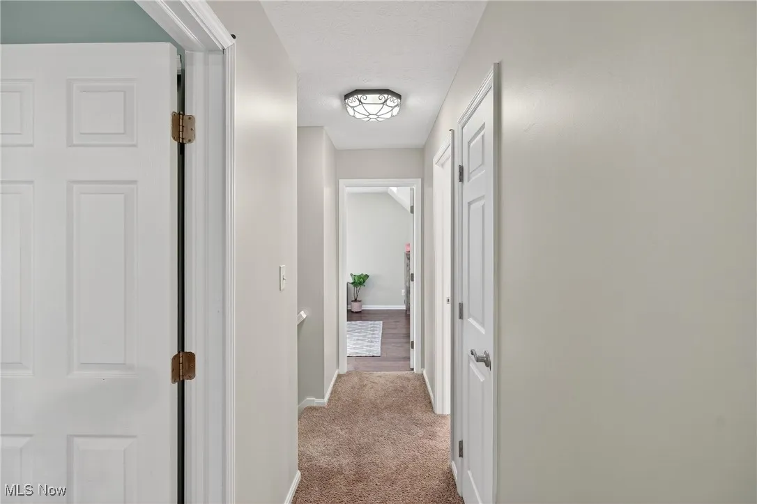 Hall with light colored carpet and a textured ceiling
