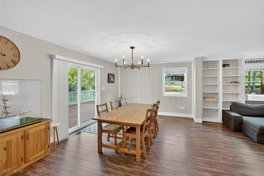 Dining area with dark wood-style floors, a textured ceiling, and a chandelier