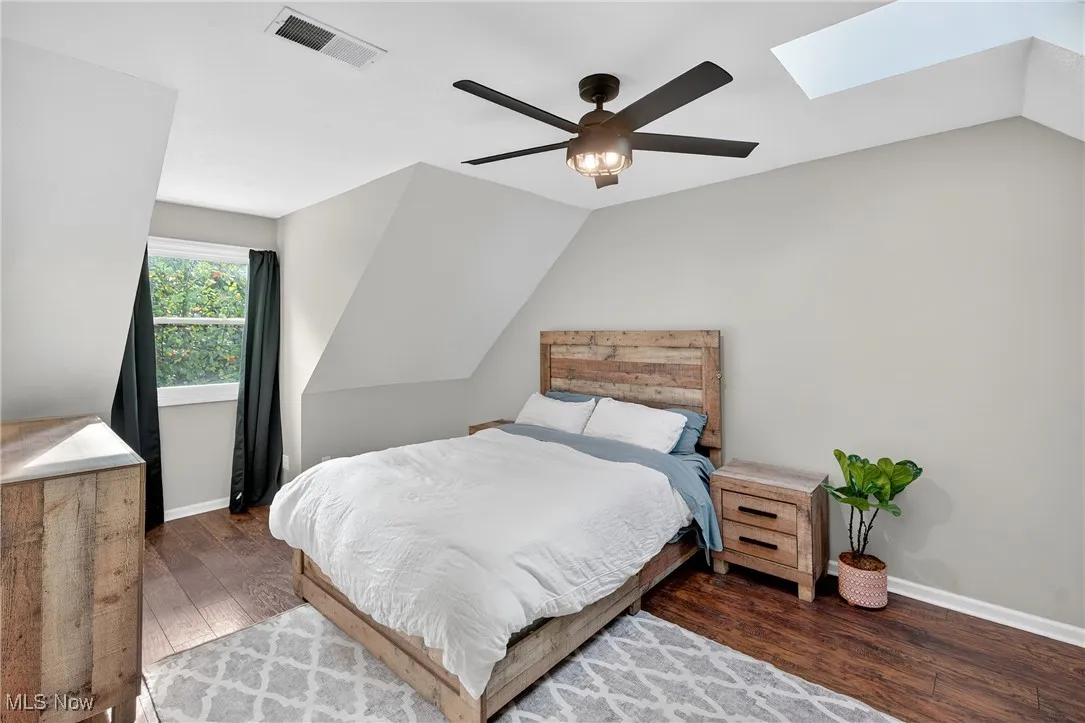 Bedroom with a skylight, dark wood-style floors, lofted ceiling, and a ceiling fan