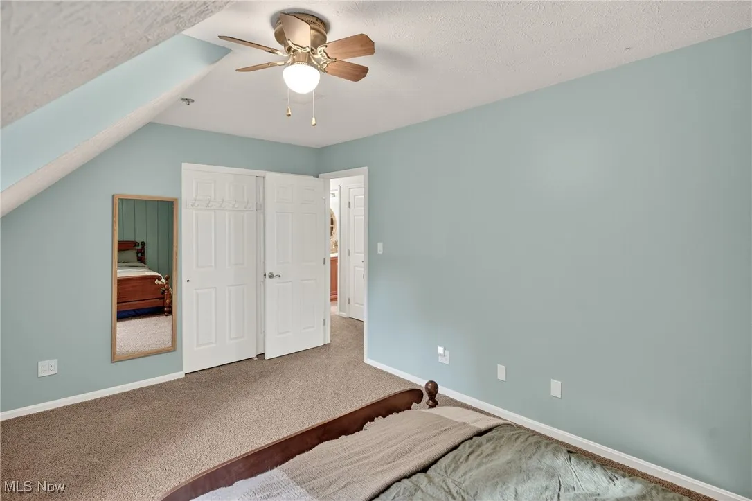 Bedroom with a textured ceiling, carpet floors, a ceiling fan, and a closet