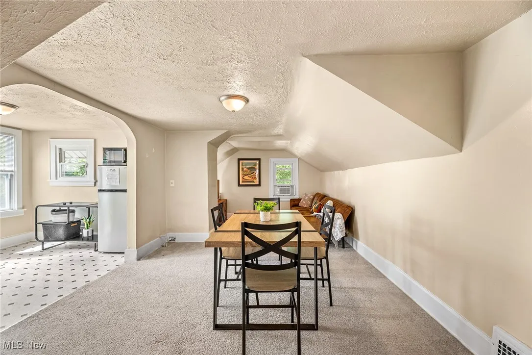 Carpeted dining room featuring a textured ceiling and arched walkways