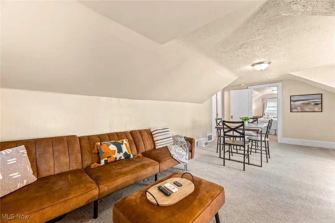 Living area with carpet floors, a textured ceiling, and vaulted ceiling
