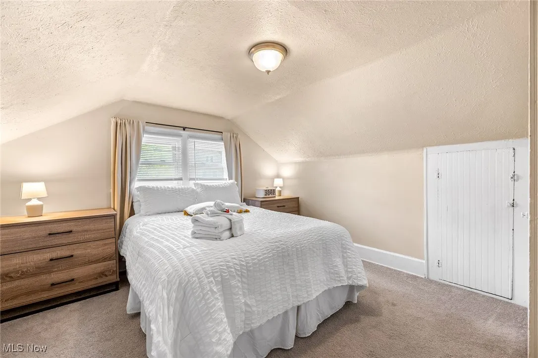 Bedroom featuring a textured ceiling, carpet floors, and vaulted ceiling