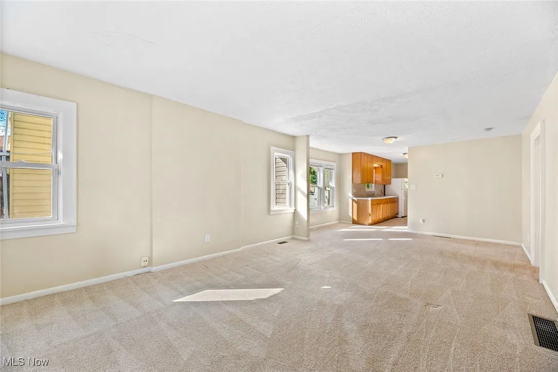 Unfurnished living room with light carpet and a textured ceiling