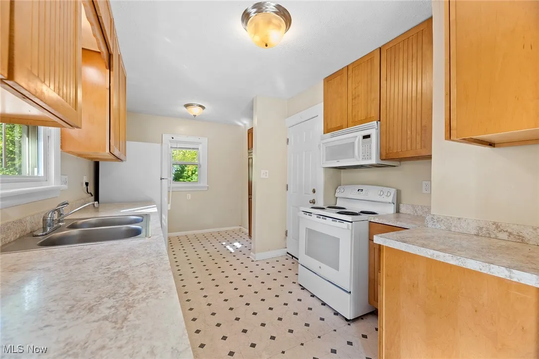Kitchen with white appliances, light countertops, and light flooring