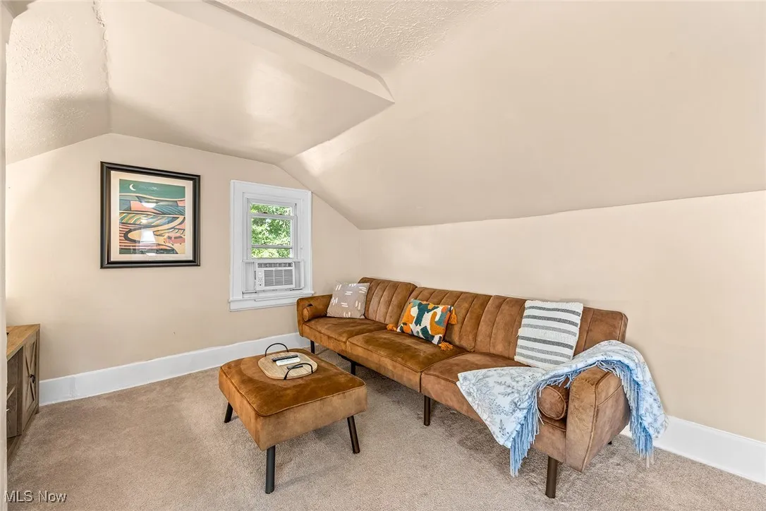 Carpeted living room featuring a textured ceiling, lofted ceiling, and cooling unit