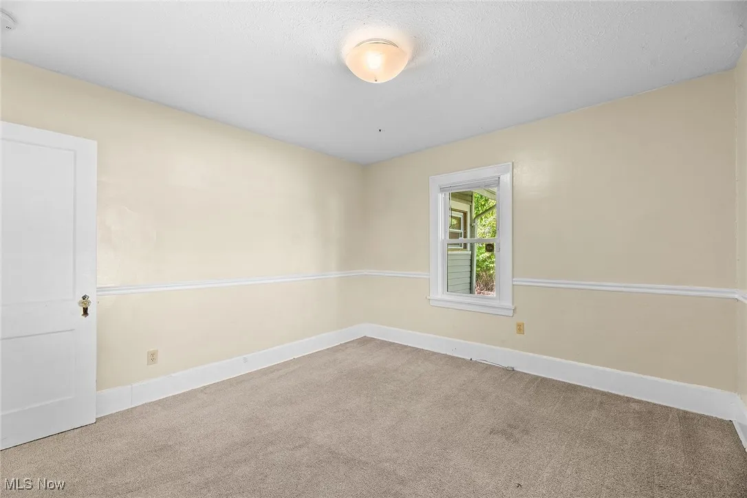 Unfurnished room featuring light carpet and a textured ceiling