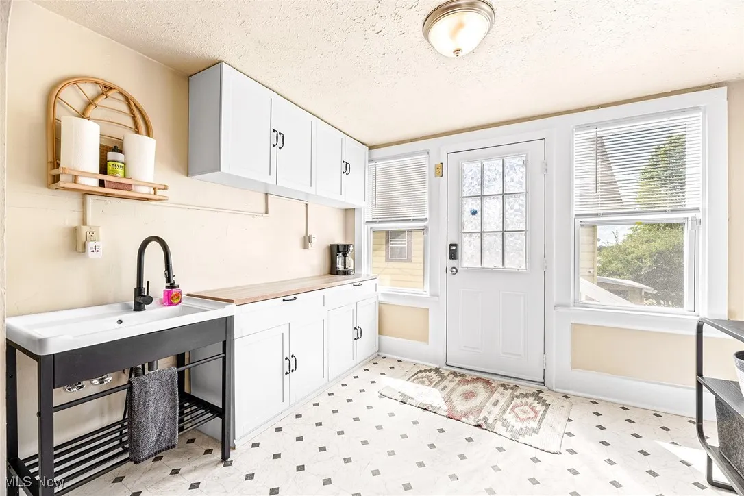 Kitchen featuring a textured ceiling, white cabinets, light floors, and butcher block countertops