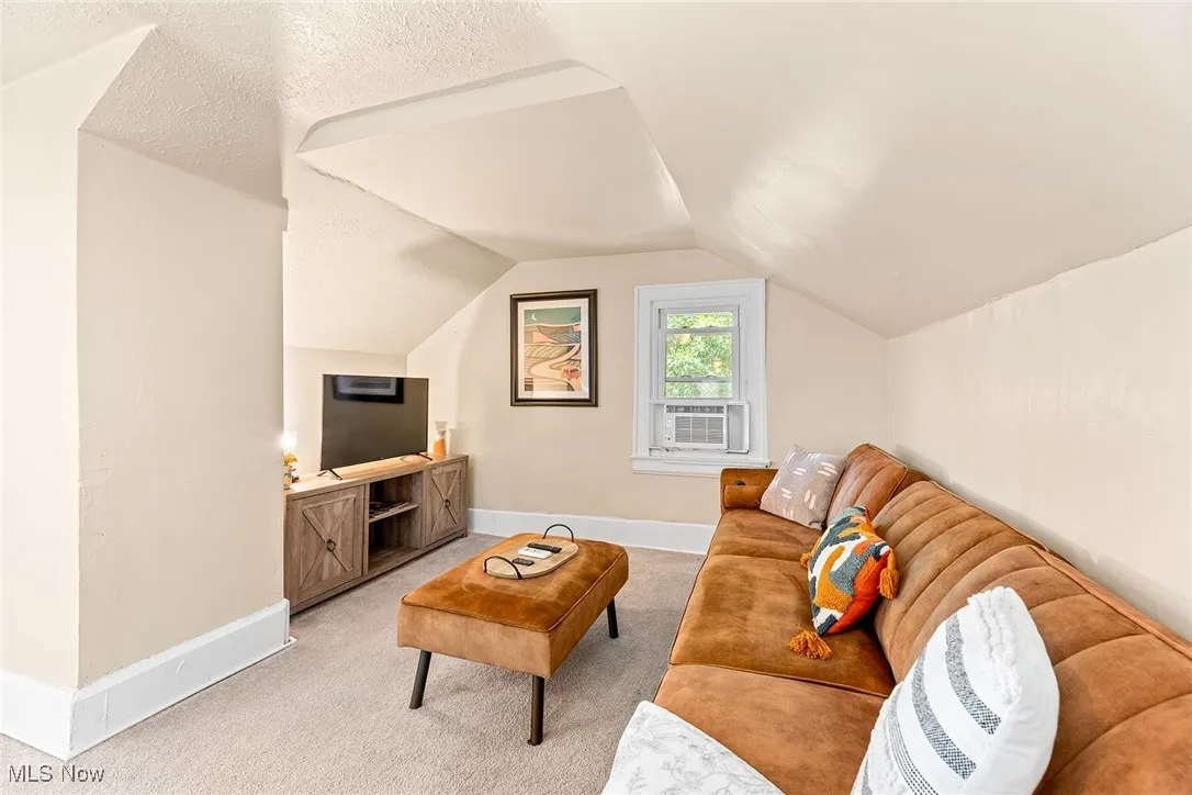 Carpeted living area with baseboards and lofted ceiling