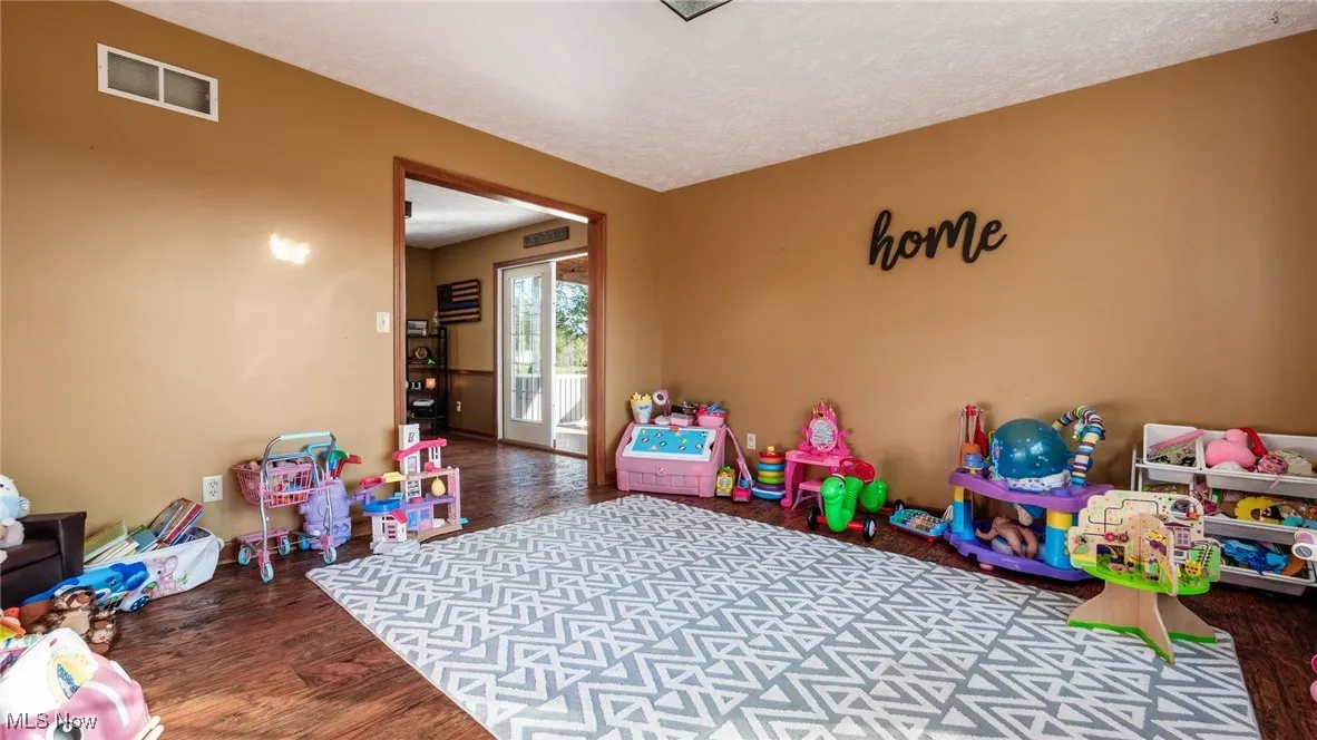 Playroom with dark wood-style floors and a textured ceiling