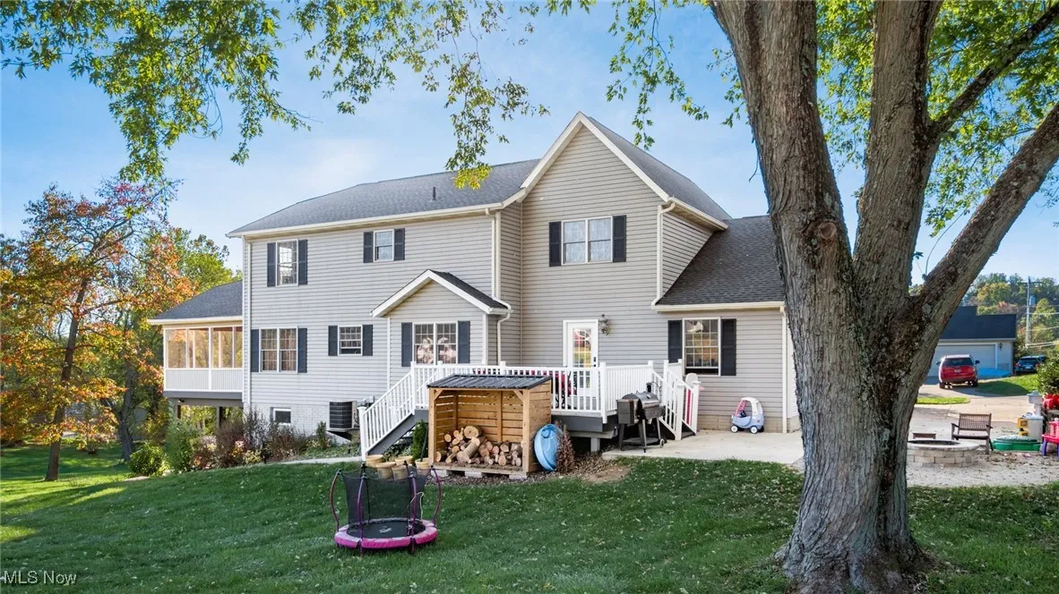 Rear view of property with a yard, stairway, a patio, and a shingled roof