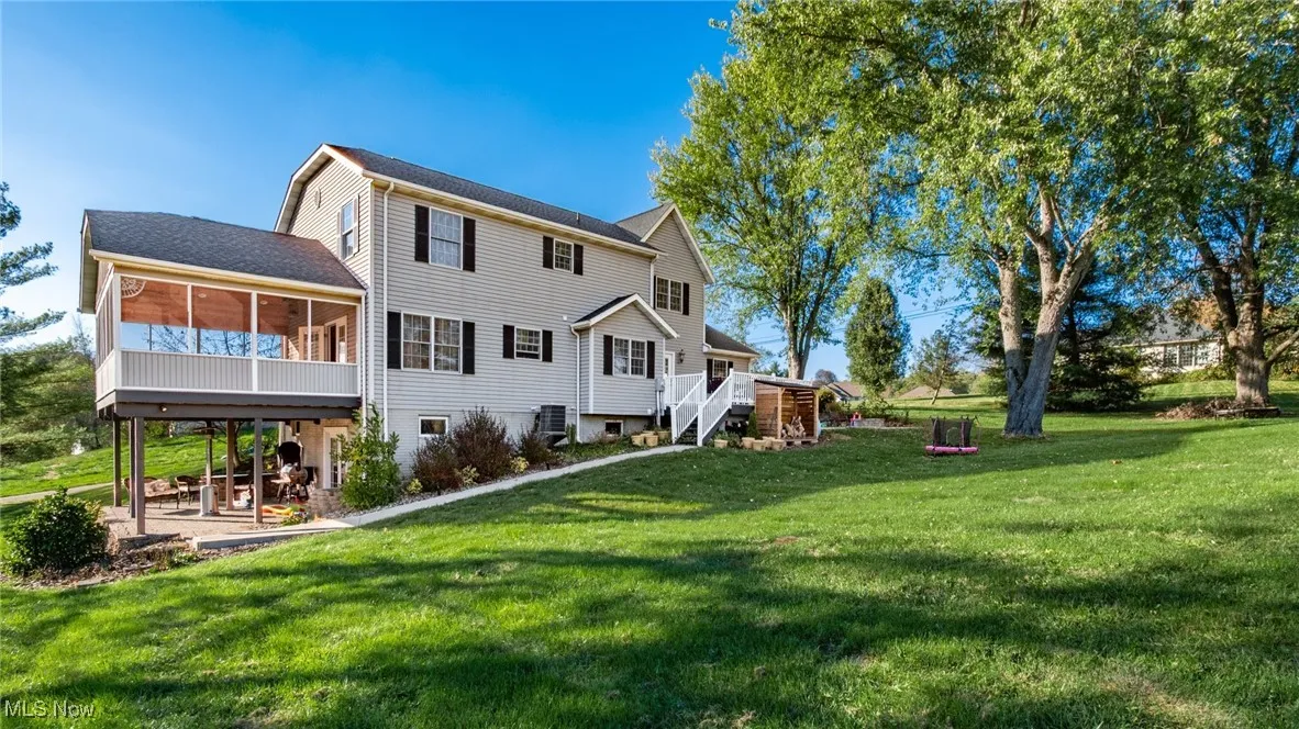 Back of house with a yard, stairs, a sunroom, and a wooden deck
