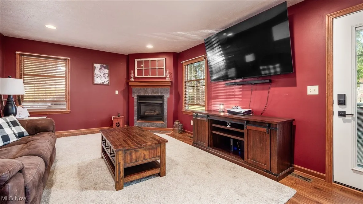 Living area with light wood-style floors, a tile fireplace, and recessed lighting