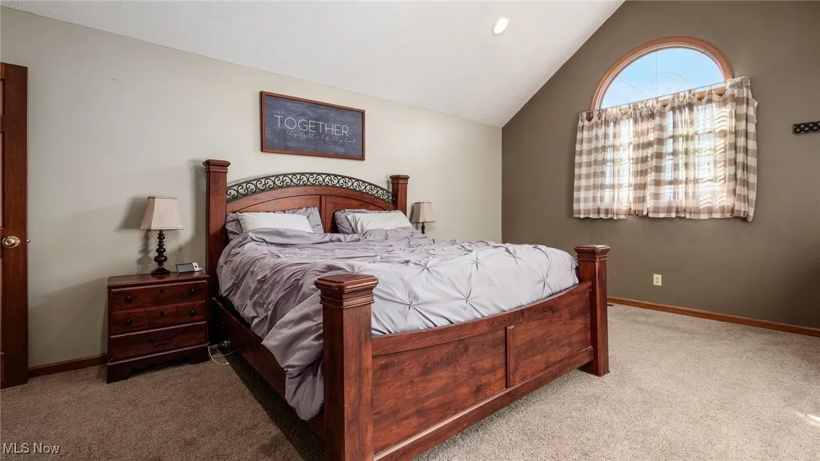 Primary Bedroom featuring vaulted ceiling and carpet