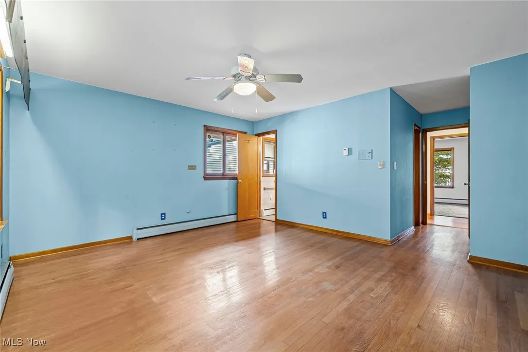 Unfurnished room with light wood finished floors, a baseboard radiator, and ceiling fan