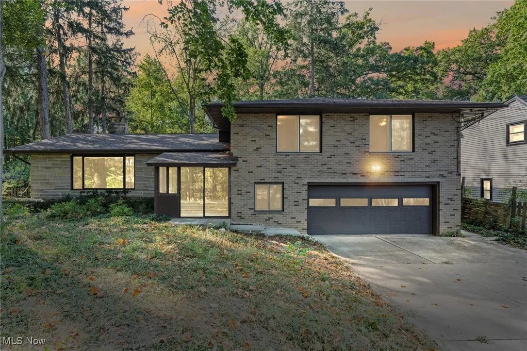 View of front facade with brick siding, a garage, and driveway