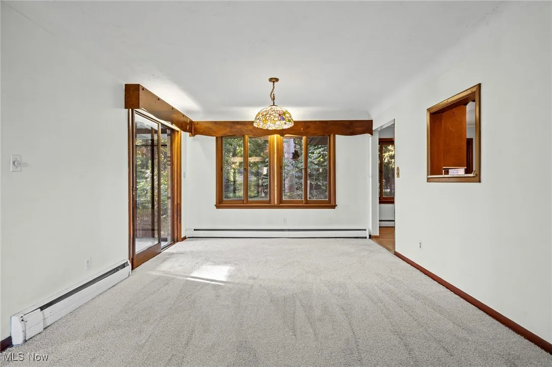 Carpeted spare room featuring a baseboard heating unit and baseboard heating