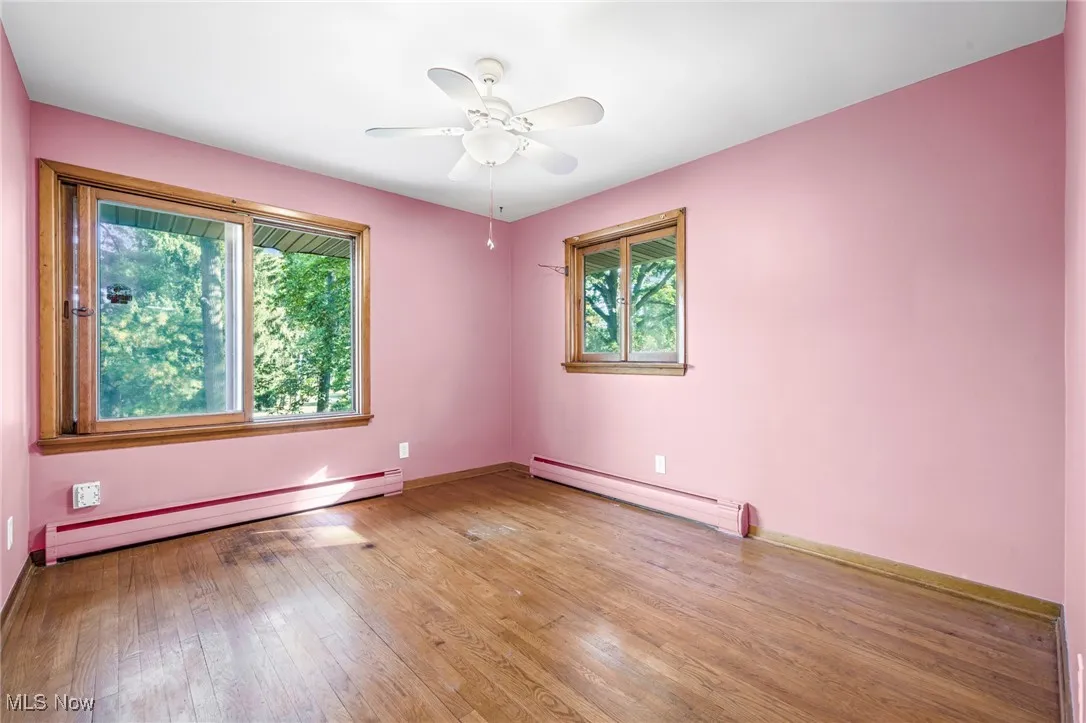 Spare room featuring baseboard heating, light wood-style floors, and ceiling fan