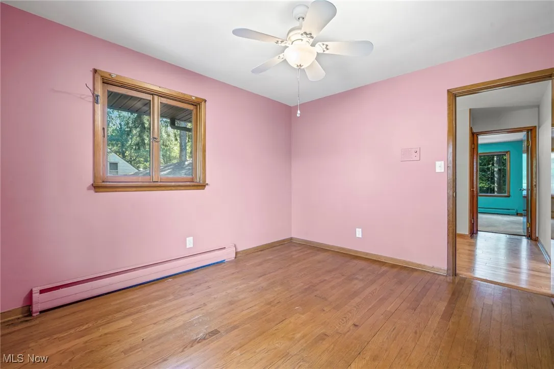 Spare room with light wood-style floors, a baseboard heating unit, healthy amount of natural light, and ceiling fan
