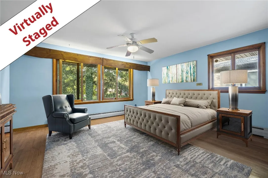 Bedroom with wood finished floors, a baseboard heating unit, and ceiling fan