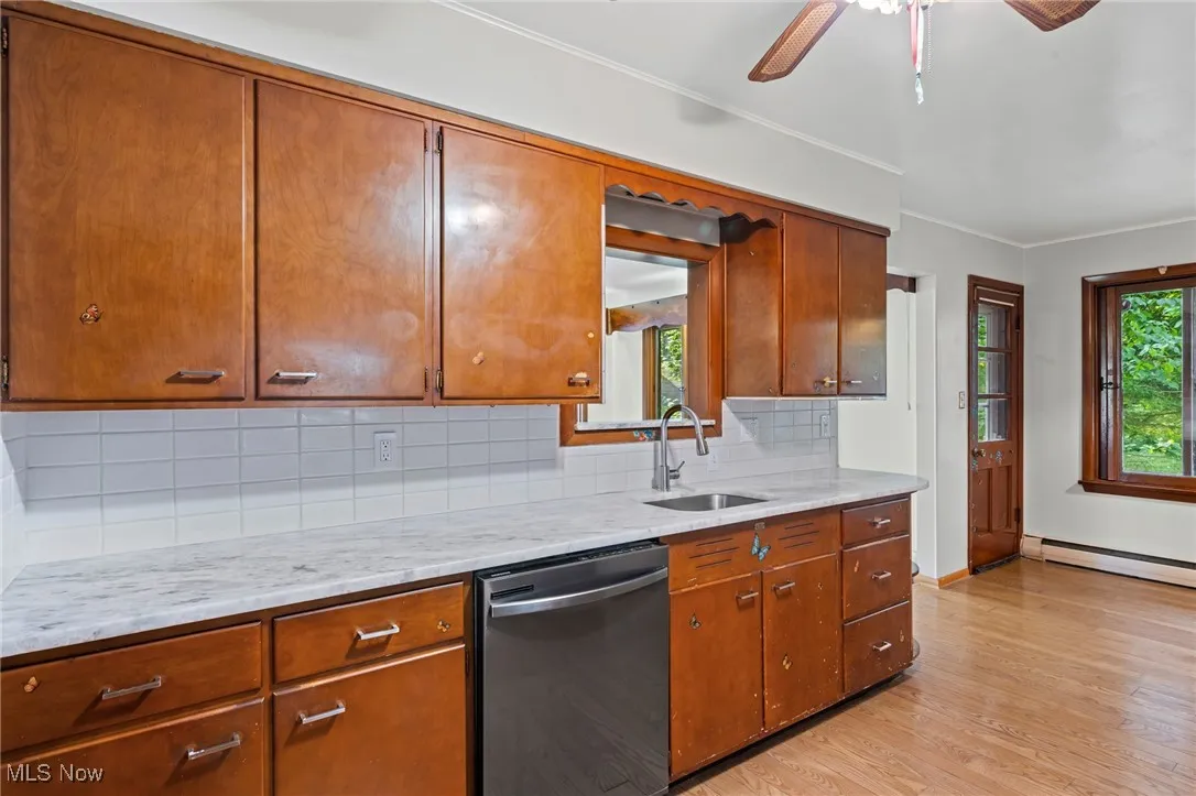 Kitchen featuring tasteful backsplash, dishwasher, light wood finished floors, brown cabinets, and crown molding