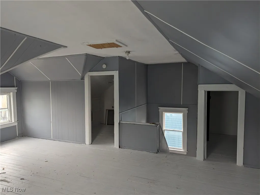 Bonus room featuring lofted ceiling, plenty of natural light, and light wood-type flooring