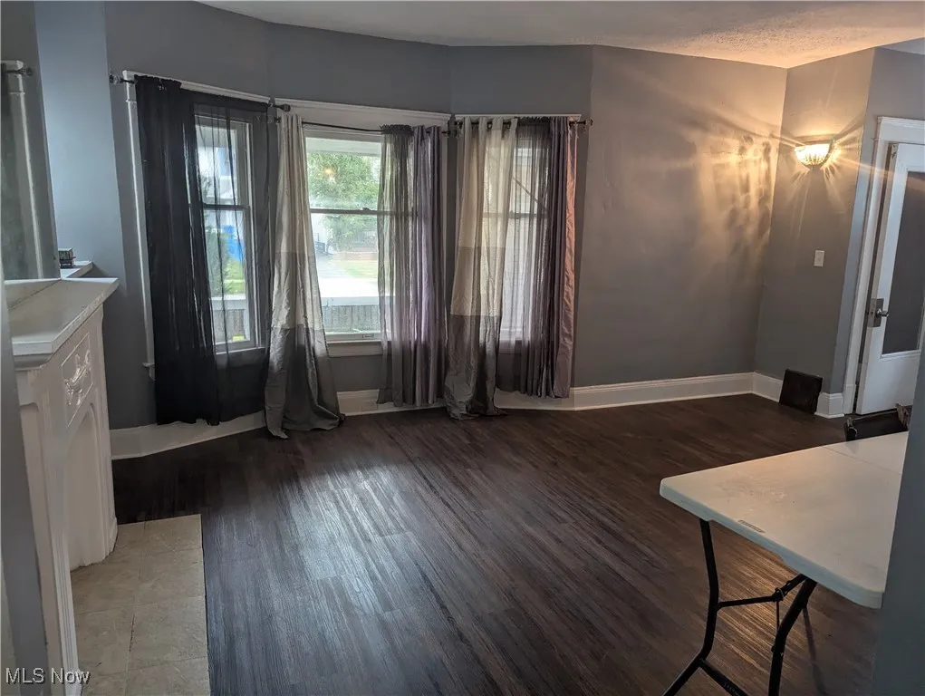 Unfurnished dining area with baseboards and dark wood finished floors