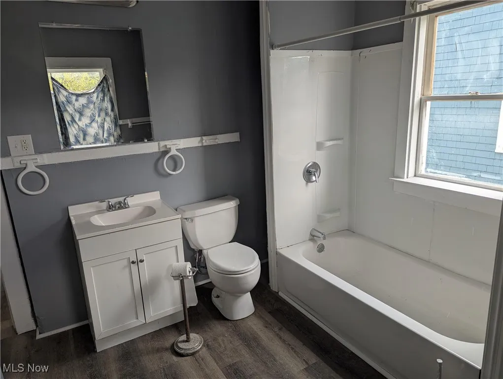 Full bath with tub / shower combination, dark wood-style floors, and vanity