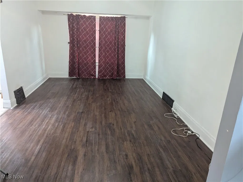 Spare room with dark wood finished floors and baseboards