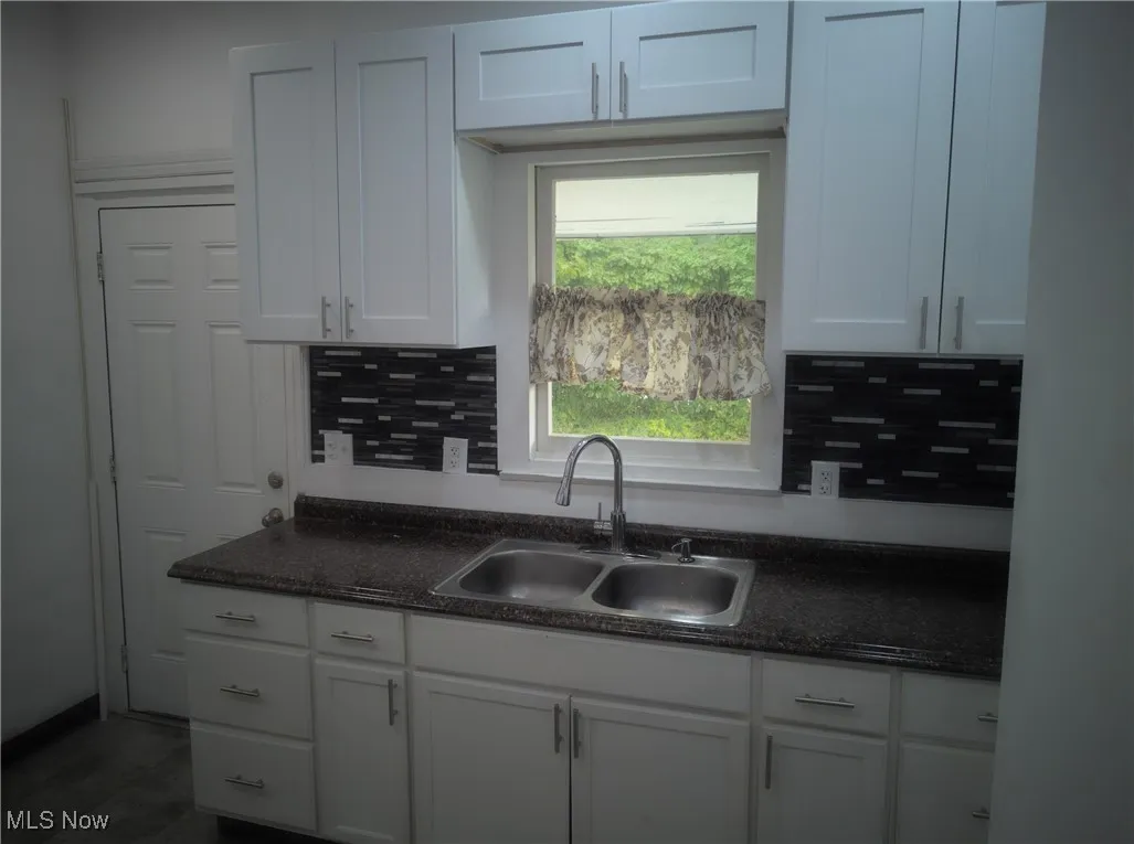 Kitchen featuring decorative backsplash and white cabinetry