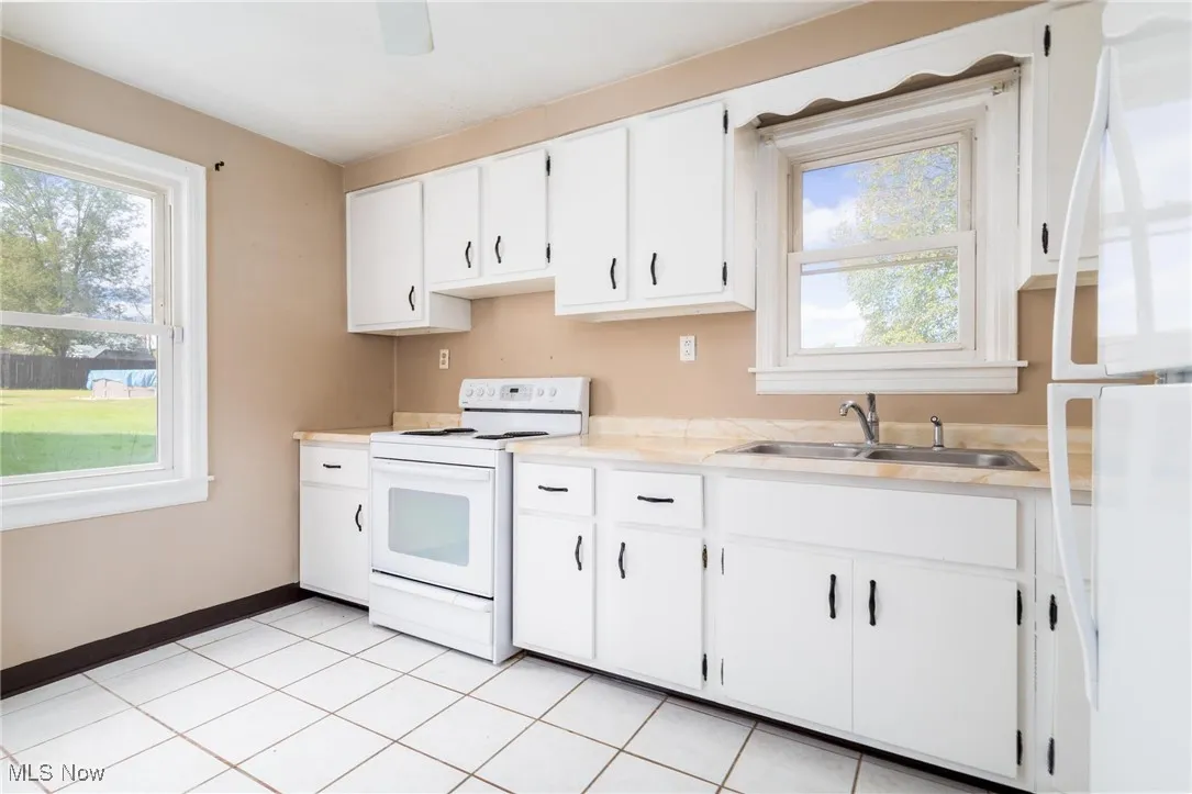 Kitchen featuring white appliances, white cabinetry, light countertops, and light tile patterned floors