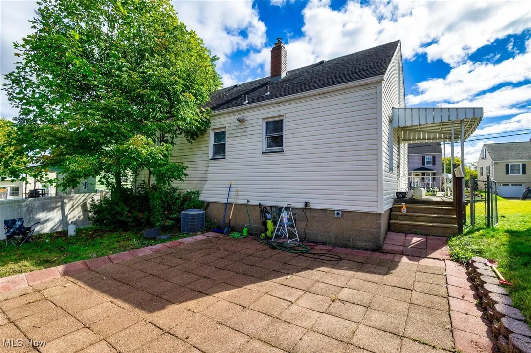 Back of house featuring a wooden deck, a chimney, crawl space, a patio area, and a shingled roof