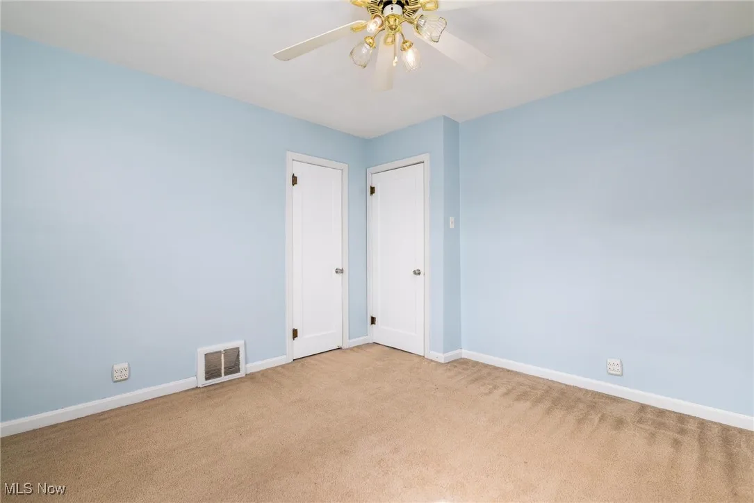 Carpeted empty room with baseboards and ceiling fan