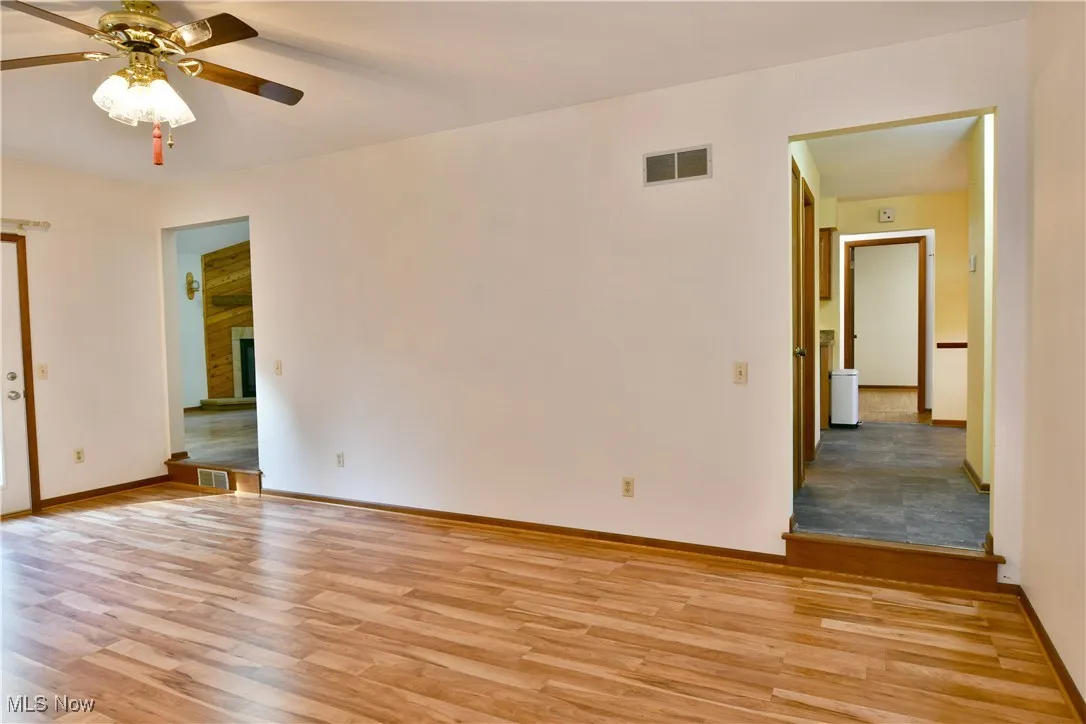 Spare room with light wood-style floors, ceiling fan, and a fireplace with raised hearth
