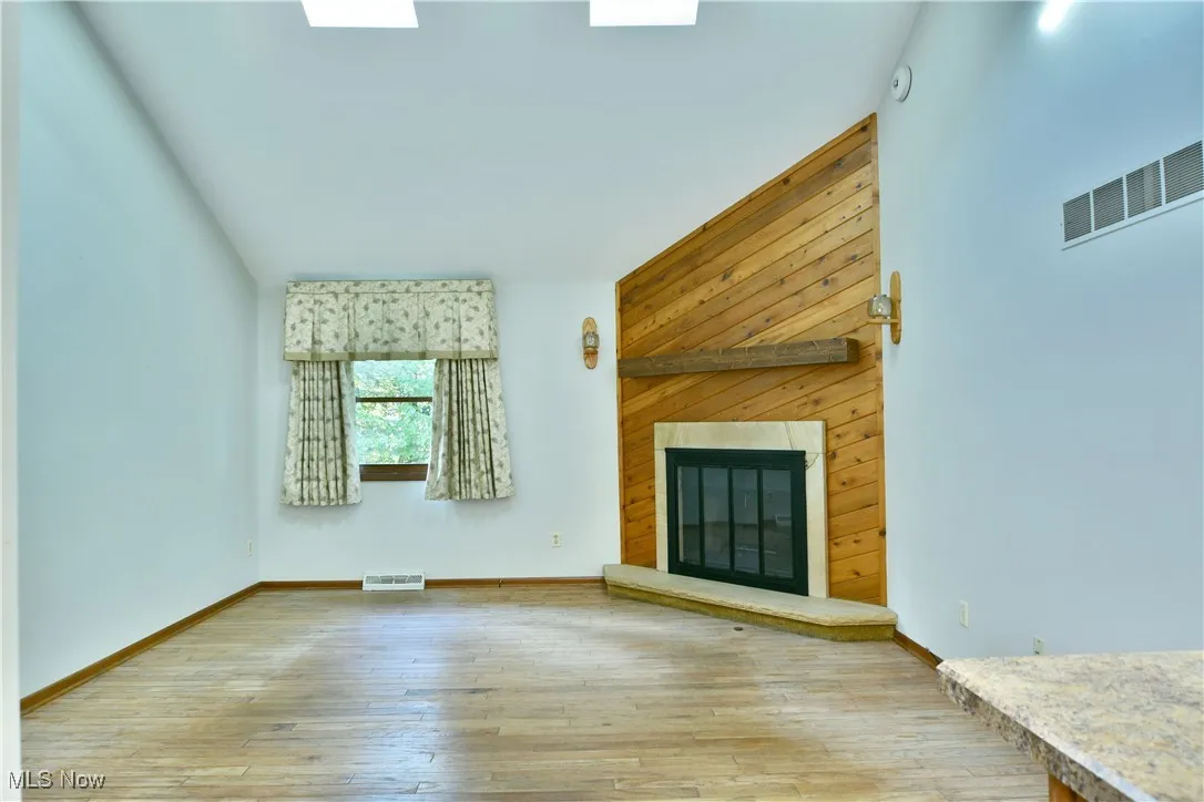 Unfurnished living room featuring light wood-type flooring and a brick fireplace