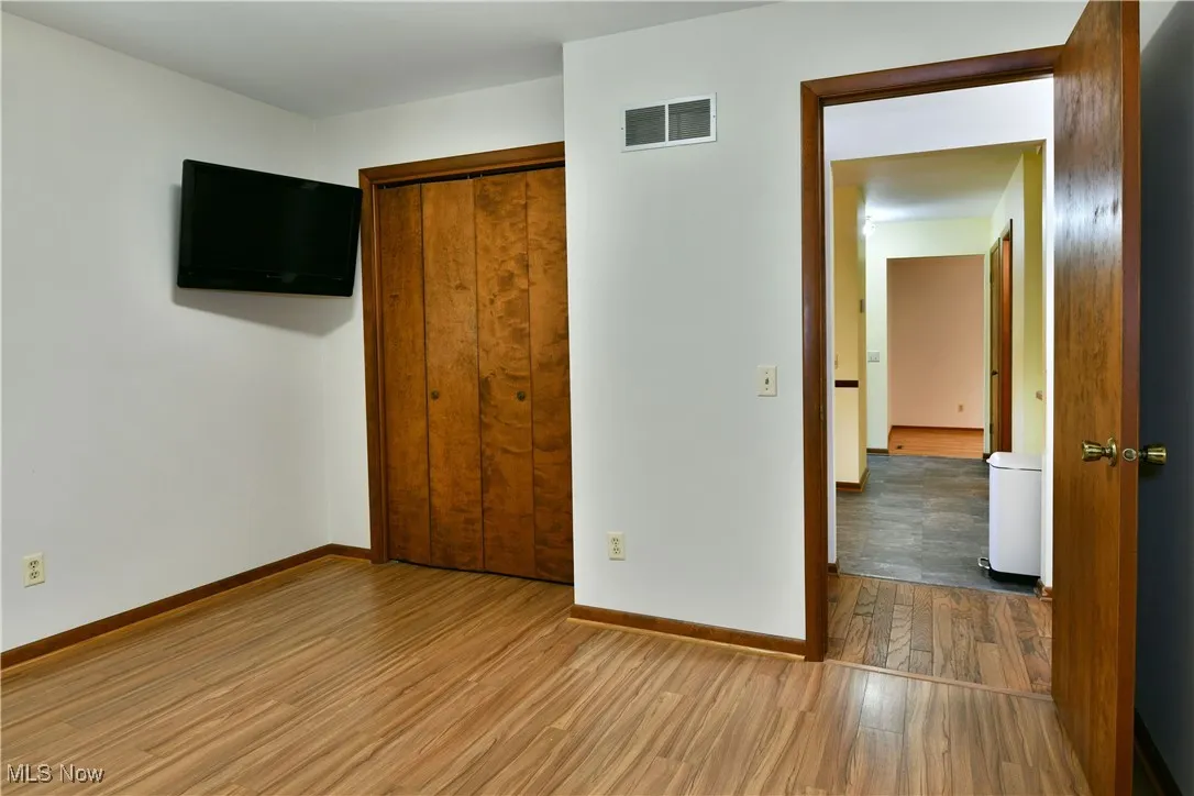 Unfurnished bedroom with wood finished floors and a closet