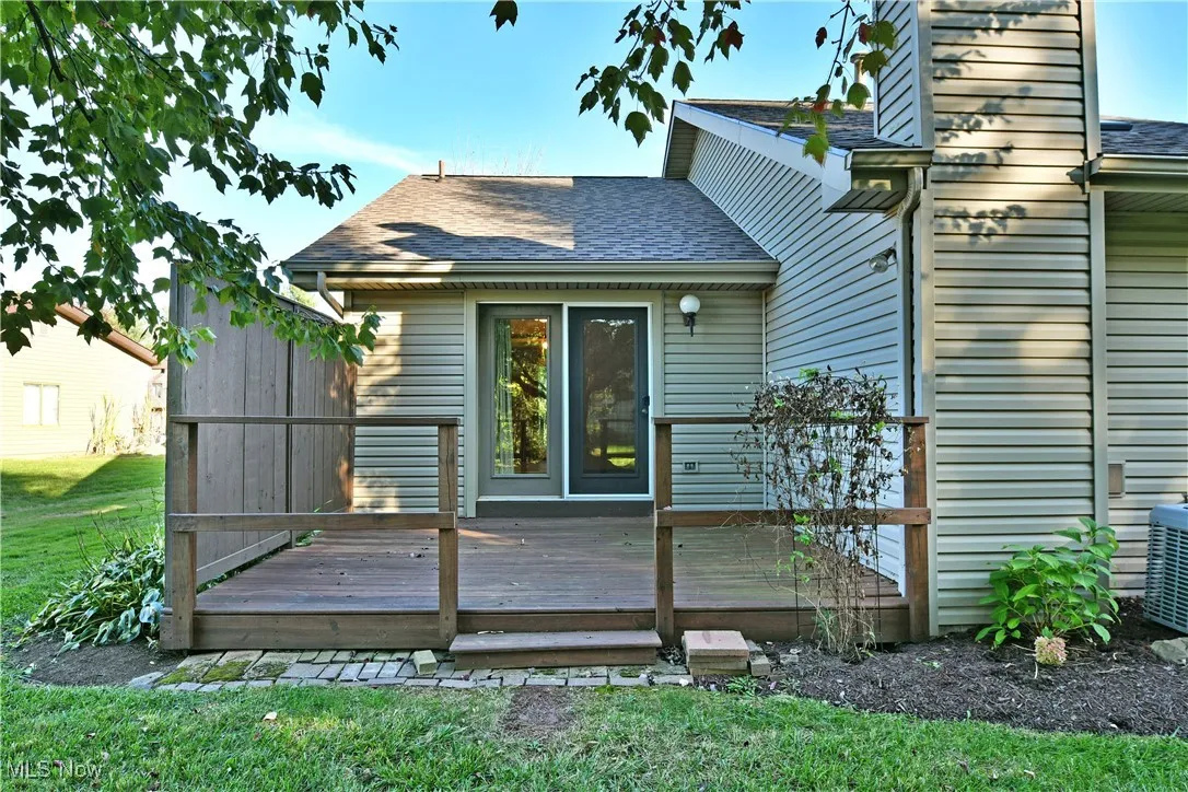 Rear view of house with roof with shingles, a deck, and a lawn