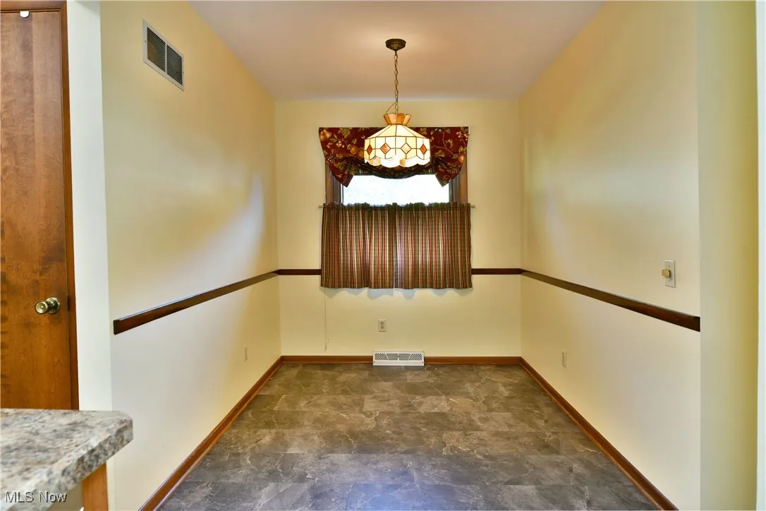 Unfurnished dining area with stone finish flooring and baseboards