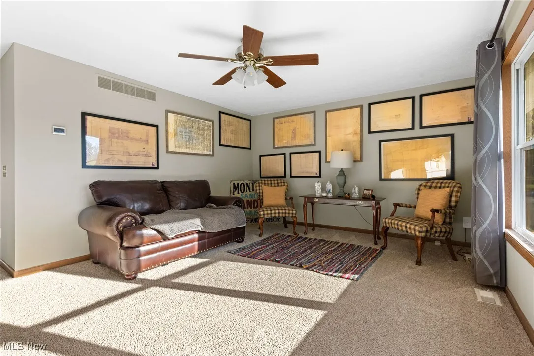 Living area featuring light carpet and a ceiling fan