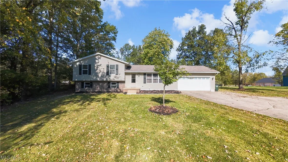Split level home with concrete driveway, a front lawn, and an attached garage