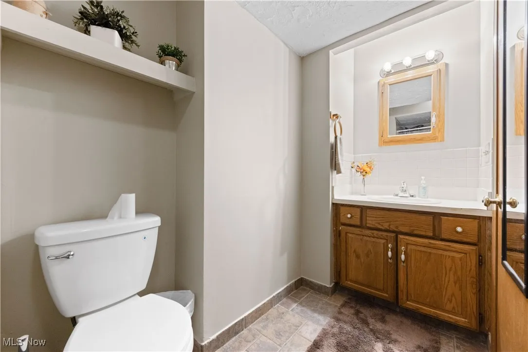 Half bath with vanity, a textured ceiling, and decorative backsplash