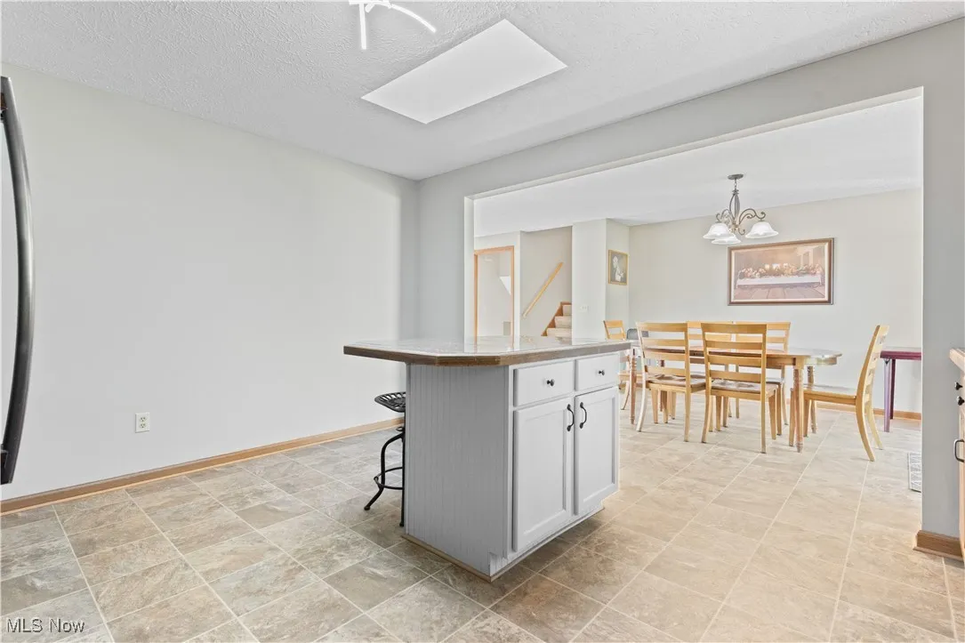 Kitchen featuring a skylight, a breakfast bar, pendant lighting, a textured ceiling, and light countertops