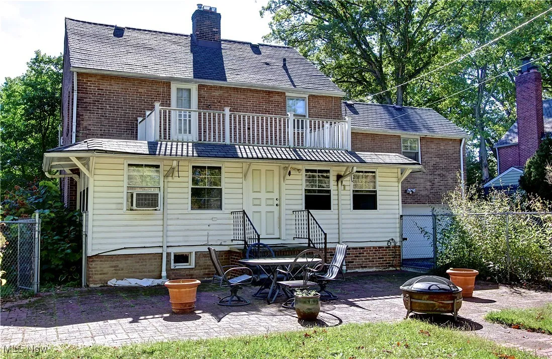 Back of house featuring a patio, an outdoor fire pit, a balcony, a chimney, and a gate