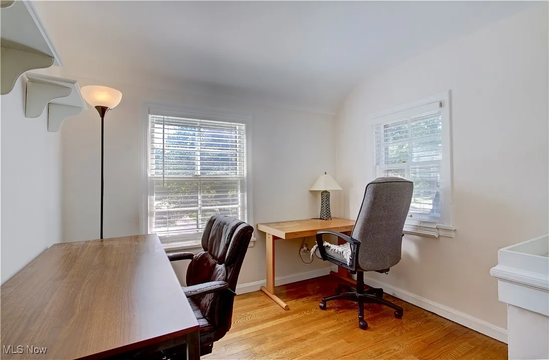 Office with light wood-style floors and lofted ceiling
