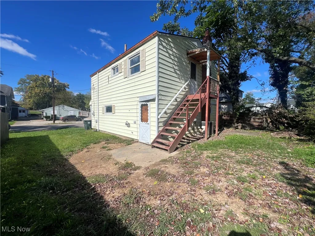 Back of property featuring stairway and a yard