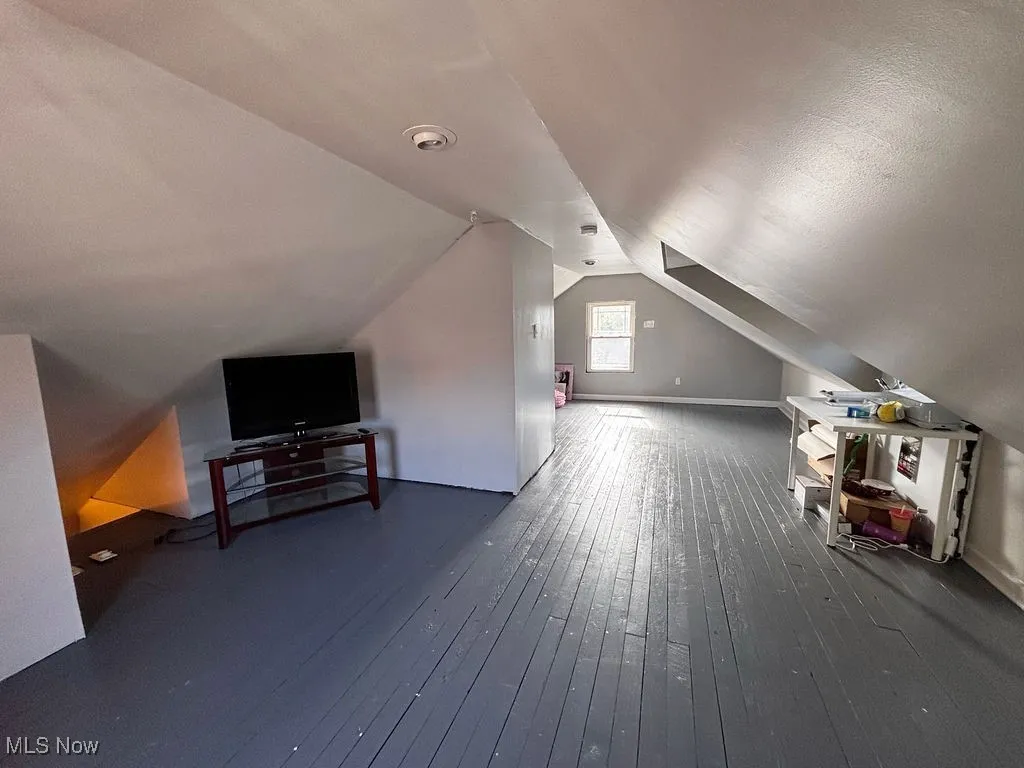 Bonus room with dark wood finished floors and lofted ceiling