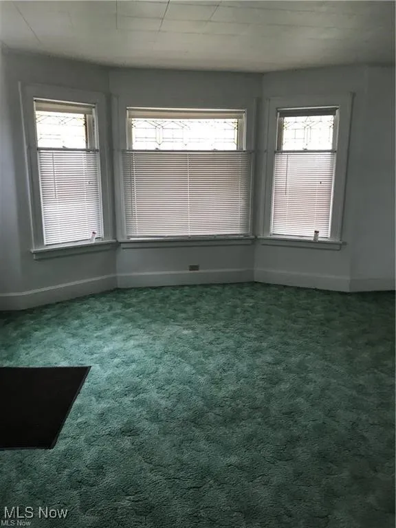 Empty room featuring dark carpet and baseboards
