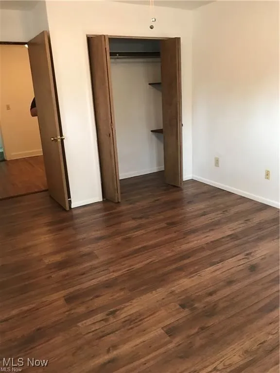 Unfurnished bedroom with dark wood finished floors and a closet