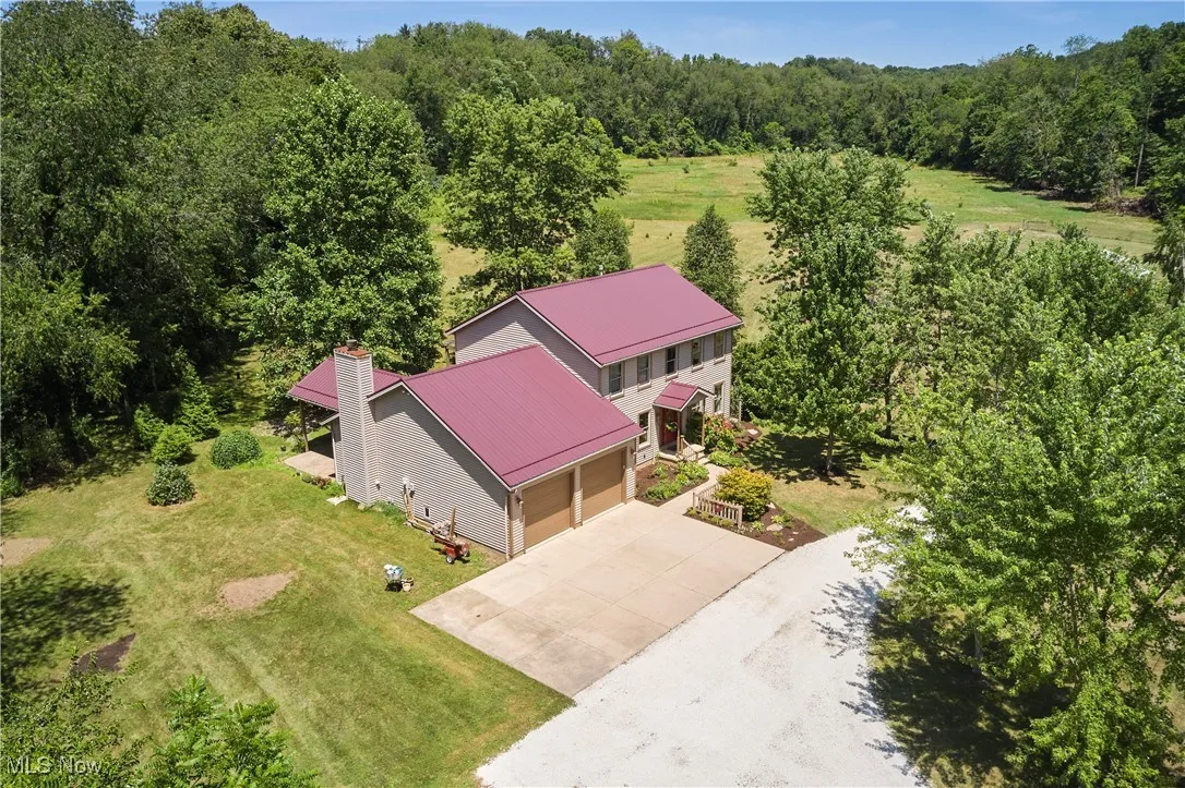 Aerial view of property and surrounding area with a forest